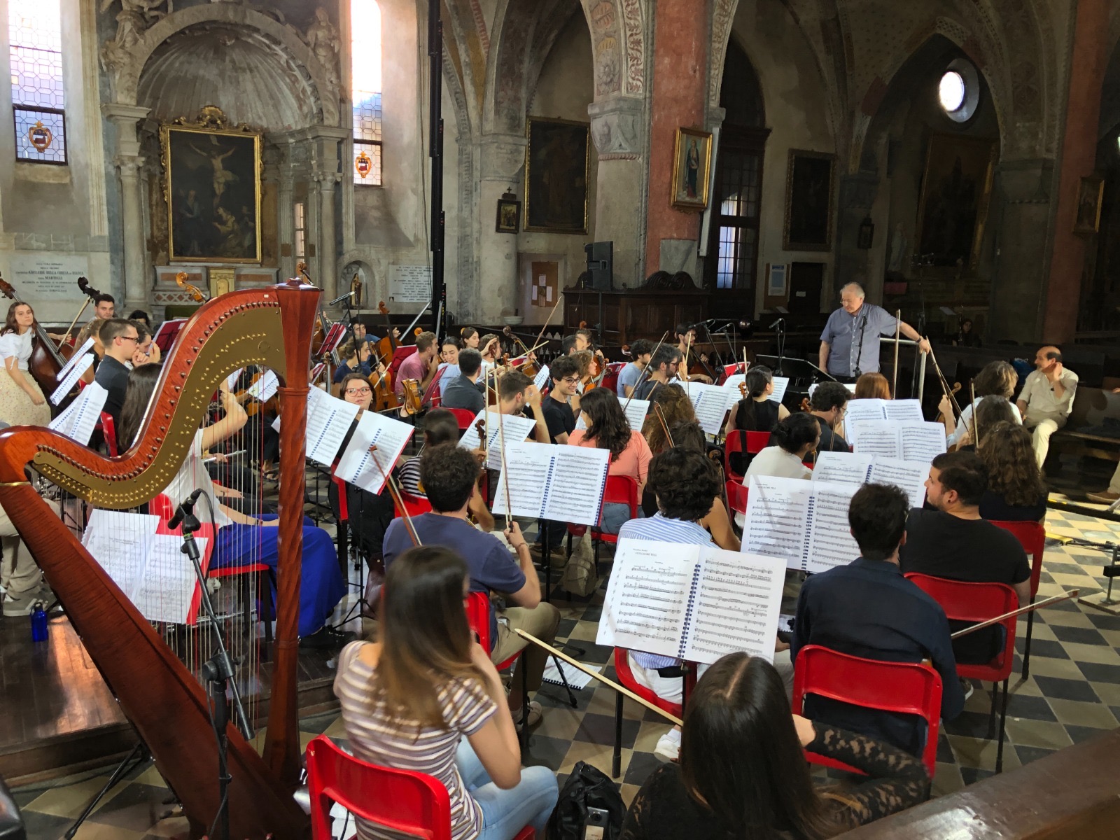 Registrazione di un'orchestra in una chiesa barocca con arpa in primo piano